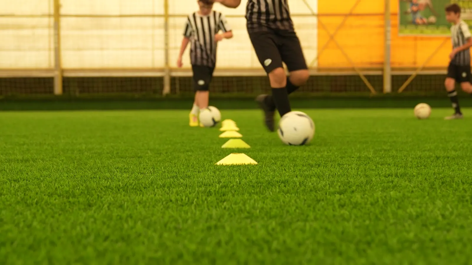 Close-up of players dribbling through yellow training cones