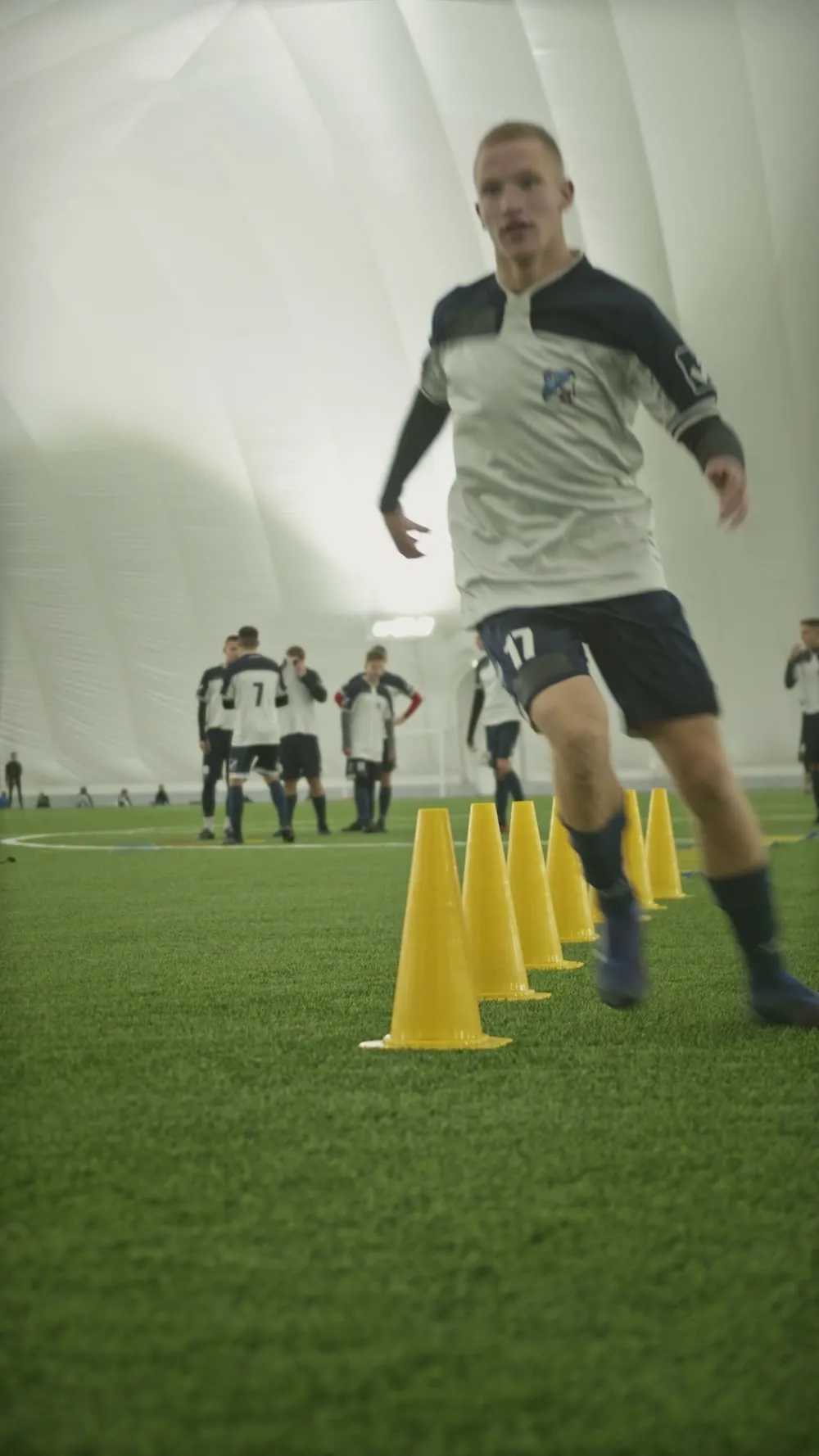Teen player sprinting through a cone drill indoors