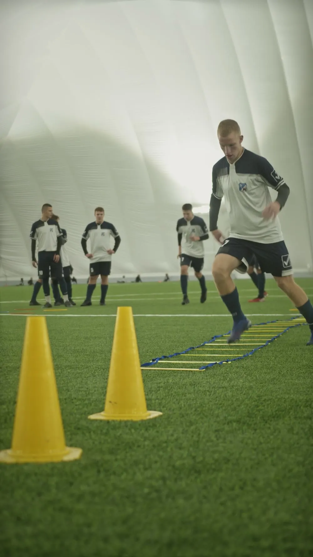 Player working through an agility ladder inside an indoor training dome