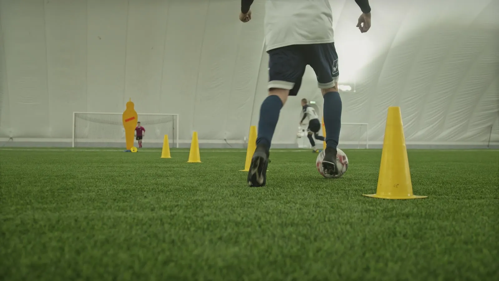 Player dribbling through cones inside a training dome