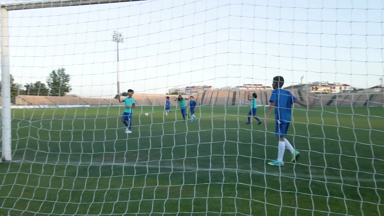 Young players seen through the goal net during a match